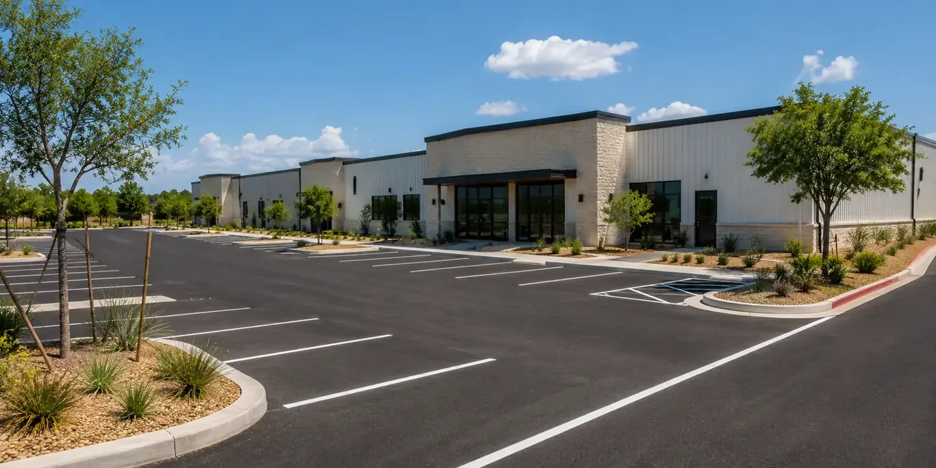 Freshly sealed and striped asphalt car park in front of a new stone-and-metal commercial building
